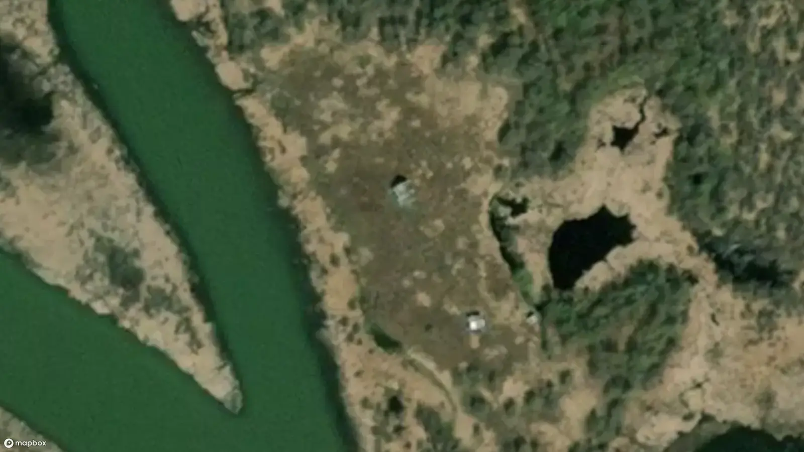 A satellite view of the two rivers dividing at Dètaè?aa. The roofs of two small cabins can be seen in the clearing, just off the river bank.